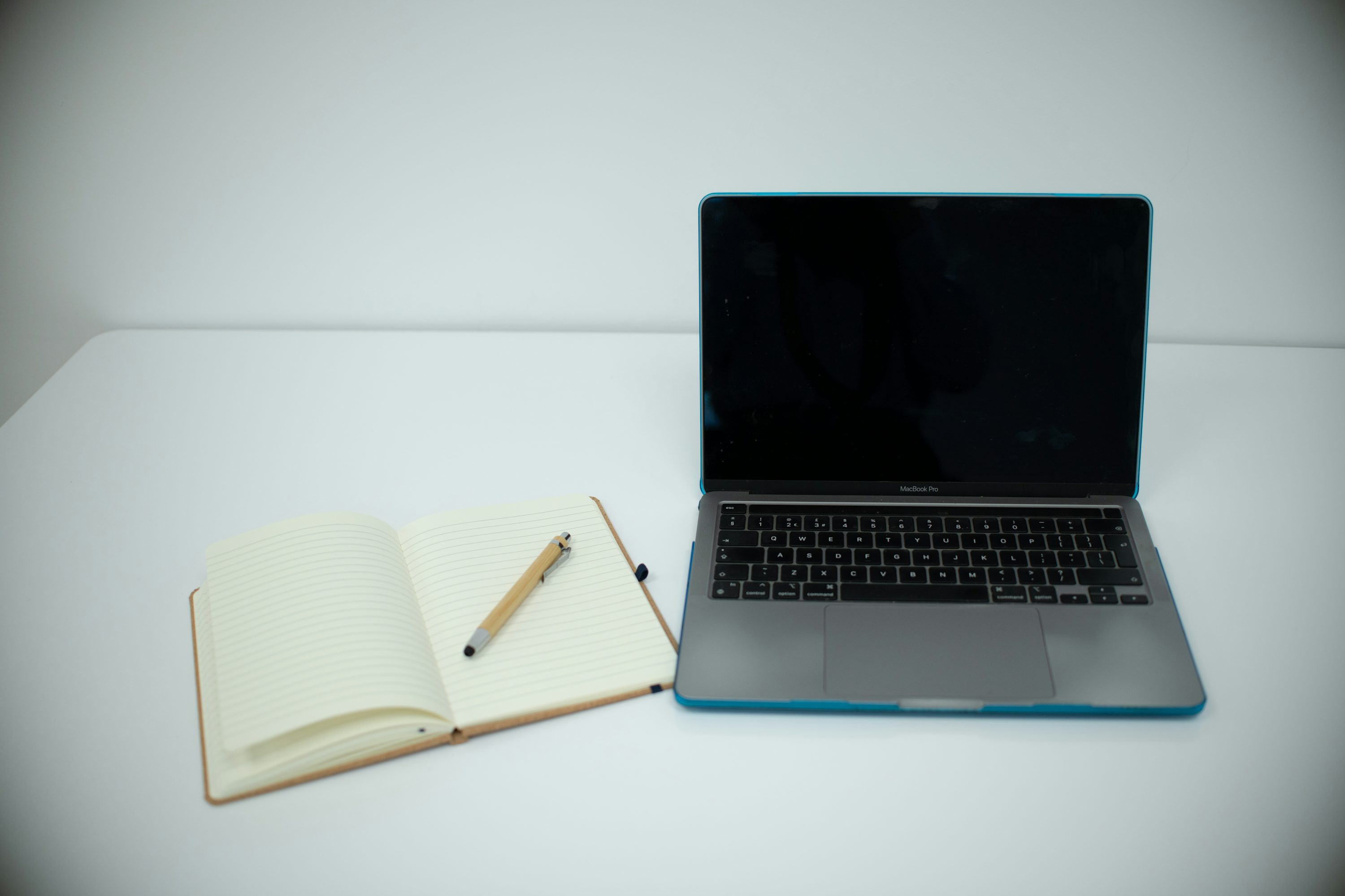 Ordinateur portable et carnet ouverts sur un bureau blanc pour cadrer un audit de marque.